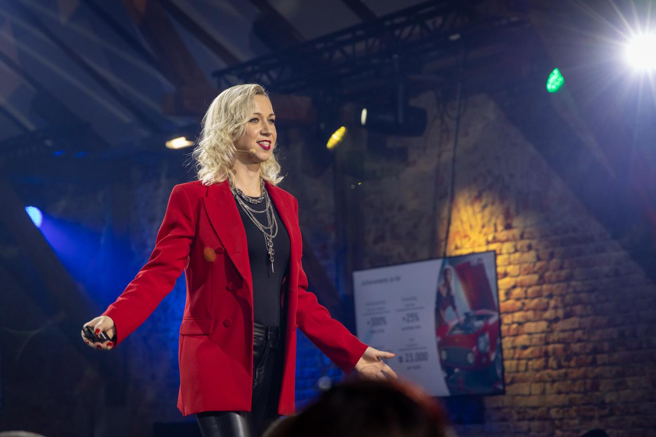 Denise Stadtegger während einer Keynote im roten Blazer
